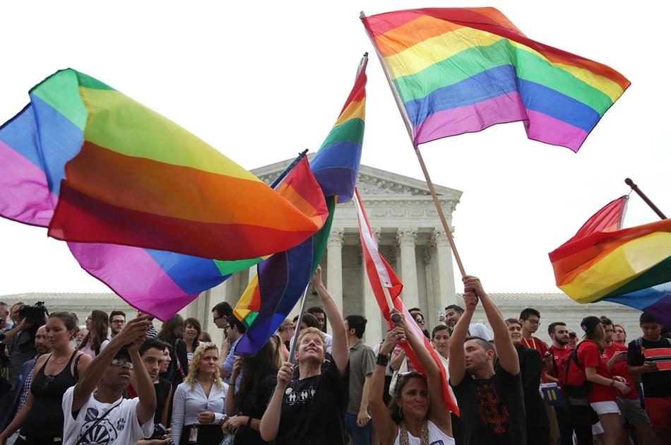 人们在美国国旗前挥舞着彩虹旗.S. 最高法院
